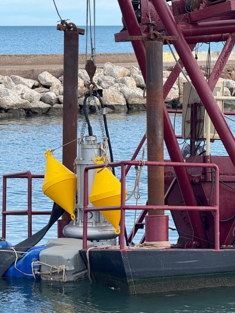 Bomba sumergible Toyo colgada de la grúa del pontón, estabilizada con boyas